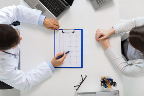 medicine, healthcare, cardiology and people concept - doctor with cardiogram on clipboard and young patient woman meeting at hospital