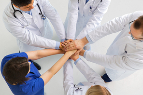 medicine, healthcare, teamwork and people concept - group of happy doctors holding hands together at hospital