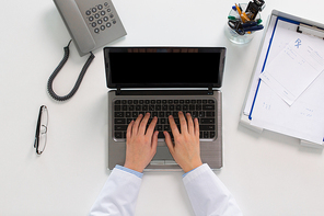medicine, healthcare and people concept - woman doctor hands typing laptop computer at table in clinic