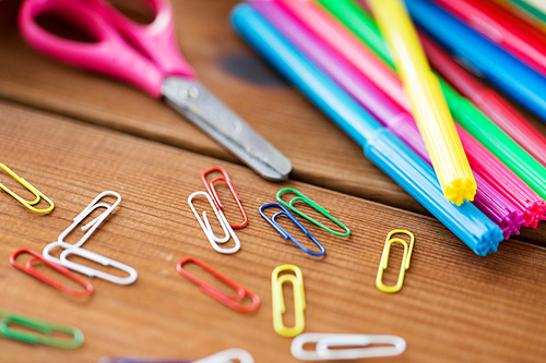 education, school supplies, art, creativity and object concept - close up of felt pens with clips and scissors on wooden table