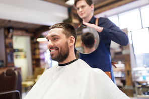 grooming, hairstyle and people concept - man and hairstylist or hairdresser with mirror at barbershop