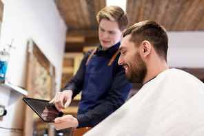 grooming, technology and people concept - hairdresser or barber showing tablet pc computer to man at barbershop