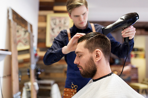 grooming, hairdressing and people concept - man and hairstylist or barber with fan drying hair at barbershop