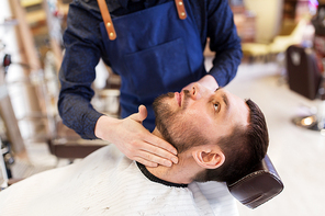 grooming and people concept - barber applying aftershave lotion to male neck at barbershop