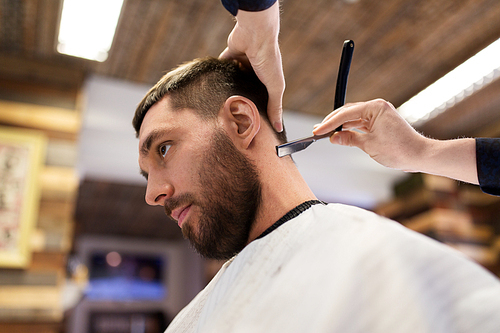 grooming and people concept - man and barber with straight razor shaving neck hair at barbershop