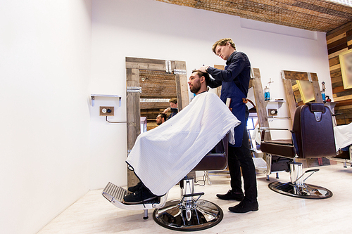 grooming, hairdressing and people concept - man and barber cutting hair at barbershop