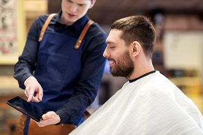 grooming, technology and people concept - hairdresser or barber showing tablet pc computer to man at barbershop