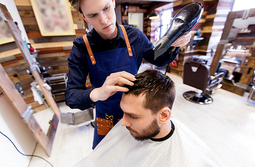 grooming, hairdressing and people concept - man and hairstylist or barber with fan drying hair at barbershop