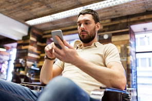 grooming, technology and people concept - man with smartphone at barbershop or hairdressing salon