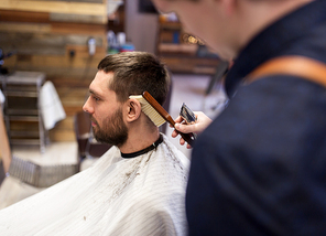 grooming, hairdressing and people concept - man and barber with trimmer and brush cleaning hair at barbershop