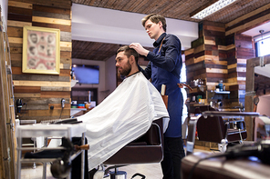 grooming, hairdressing and people concept - man and barber styling hair at barbershop