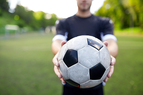 sport, football training and people - soccer player hands holding ball on field