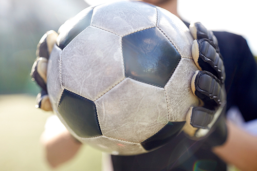 sport and people - close up of soccer player or goalkeeper holding ball at football goal on field