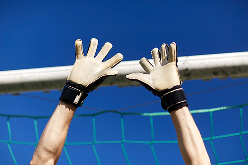 sport and people - soccer player or goalkeeper at football goal on field
