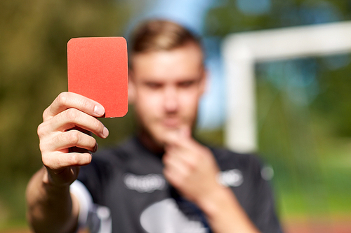 sport, caution, game and people - close up of referee hands with whistle showing red card on football field