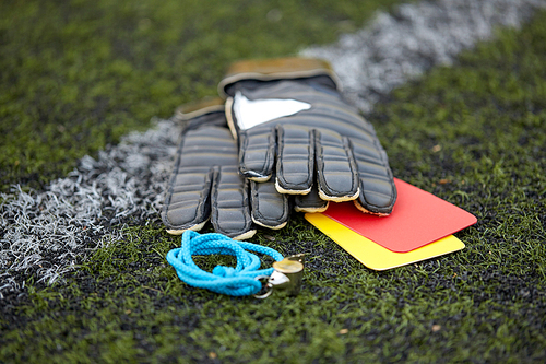 sport, soccer and game - gloves, goalkeeper referee whistle and caution cards on football field