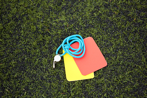 sport, soccer and game - referee whistle and caution cards on football field