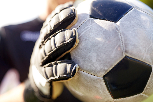 sport and people - close up of soccer player or goalkeeper holding ball at football goal on field