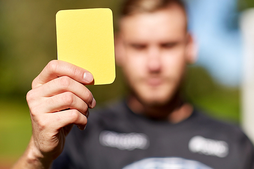 sport, caution, game and people - referee on football field showing yellow card