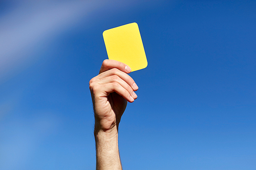 sport, caution, game and people - referee on football field showing yellow card