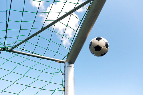 sport, soccer and game - ball flying into football goal net over blue sky