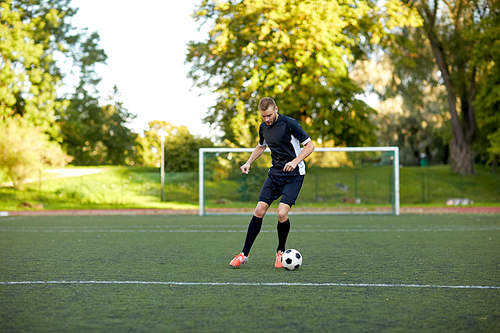 sport, football training and people - soccer player playing with ball on field