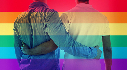 people, homosexuality, same-sex marriage, gay and love concept - close up of happy male gay couple hugging from back over rainbow flag stripes background
