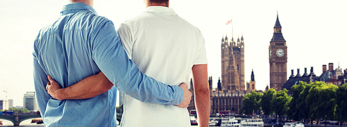 people, homosexuality, same-sex marriage, travel and love concept - close up of happy male gay couple hugging from back over big ben and houses of parliament in london background