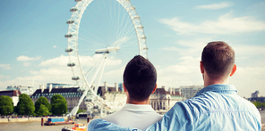 people, homosexuality, same-sex marriage, travel and love concept - close up of happy male gay couple hugging from back over london ferry wheel background