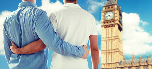 people, homosexuality, same-sex marriage, travel and love concept - close up of happy male gay couple hugging from back over big ben tower in london background
