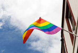 homosexuality, symbolic and gay pride concept - close up of rainbow flag waving on building
