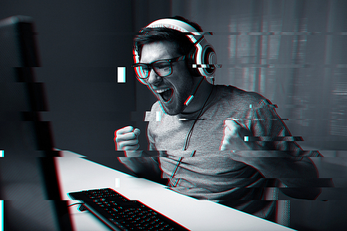 technology, entertainment and people concept - happy young man in eyeglasses with headset playing and winning computer game at home and streaming playthrough or walkthrough video, glitch effect