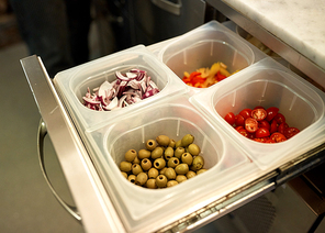 cooking, storage and food concept - containers with olives, chopped cherry tomatoes and red onion at restaurant kitchen