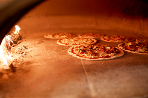food, italian kitchen and cooking concept - pizza baking in oven at pizzeria