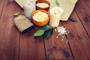 beauty, spa, therapy, natural cosmetics and wellness concept - close up of body scrub with  himalayan pink salt and candles on wood