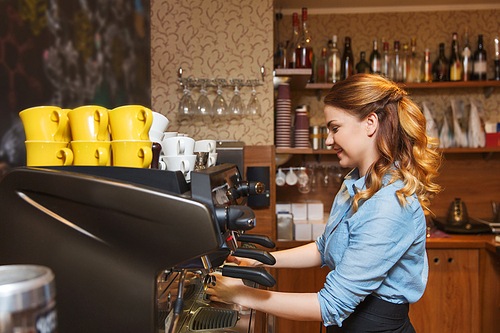 equipment, coffee shop, people and technology concept - barista woman making coffee by espresso machine at cafe bar or restaurant kitchen
