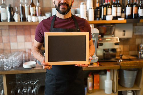 small business, people and service concept - happy man or waiter with blank blackboard at bar
