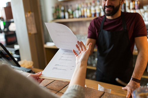 small business, people and service concept - bartender and customer menu at bar or coffee shop