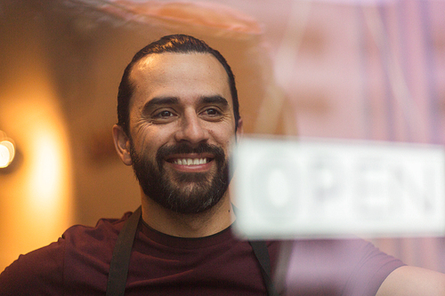 small business, people and service concept - smiling man with open word on banner at bar or restaurant window