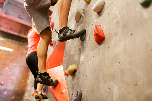 fitness, extreme sport, bouldering, people and healthy lifestyle concept - man and woman exercising at indoor climbing gym