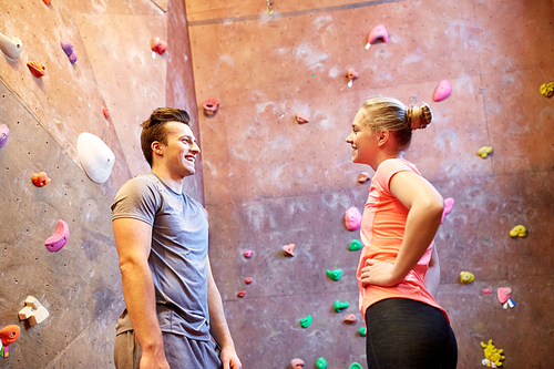 fitness, extreme sport, bouldering, people and healthy lifestyle concept - happy man and woman talking at indoor climbing gym wall