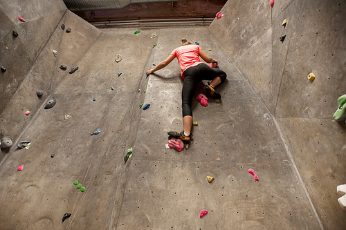 fitness, extreme sport, bouldering, people and healthy lifestyle concept - young woman exercising at indoor climbing gym