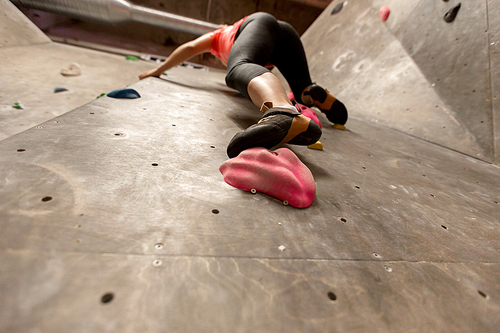 fitness, extreme sport, bouldering, people and healthy lifestyle concept - foot of young woman exercising at indoor climbing gym