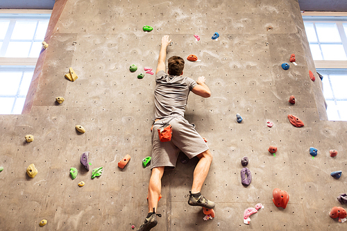 fitness, extreme sport, bouldering, people and healthy lifestyle concept - young man exercising at indoor climbing gym