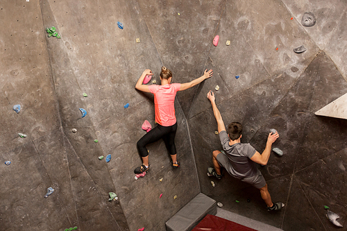 fitness, extreme sport, bouldering, people and healthy lifestyle concept - man and woman exercising at indoor climbing gym