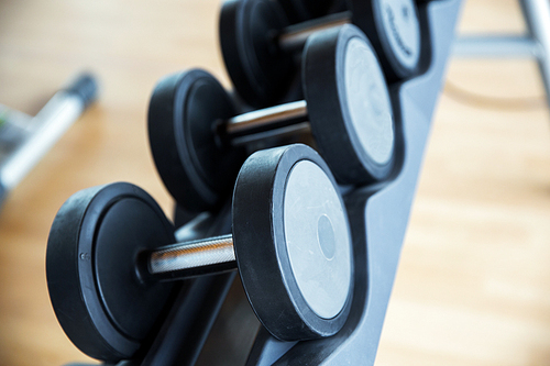 fitness, sport, exercising, weightlifting and bodybuilding concept - close up of dumbbells and sports equipment in gym