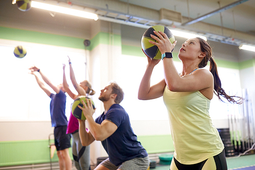 fitness, sport and exercising concept - group of people with medicine balls training in gym