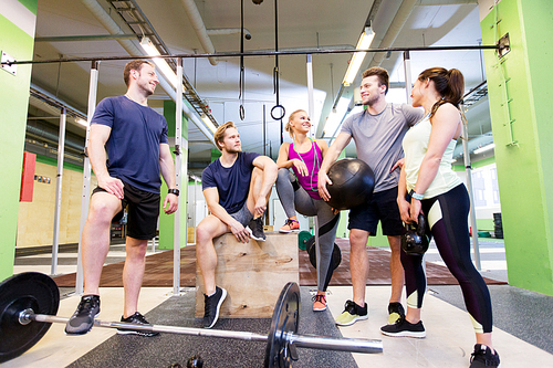 fitness, sport and healthy lifestyle concept - group of happy people with different sports equipment talking in gym