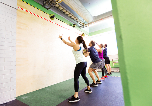 fitness, sport and exercising concept - group of people with medicine balls training in gym