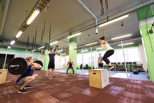 fitness, sport and exercising concept - group of people training with different equipment in gym